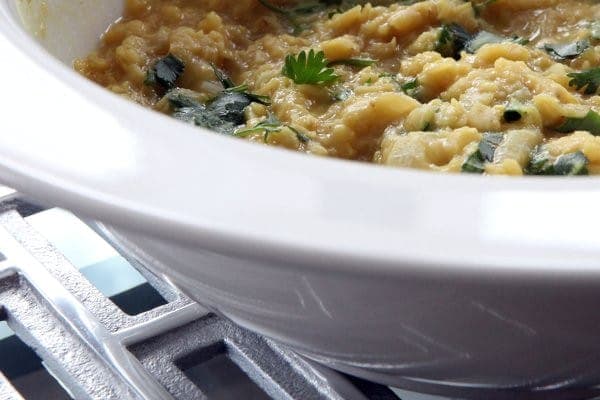 Golden lentil dal with chopped cilantro in a white pot
